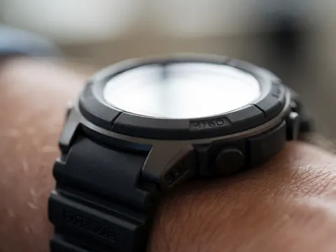 Gros plan d'une montre numérique avec un rétroéclairage vif, mettant en valeur les détails du cadran et de la sangle noire, avec une mise au point sélective sur l'appareil.