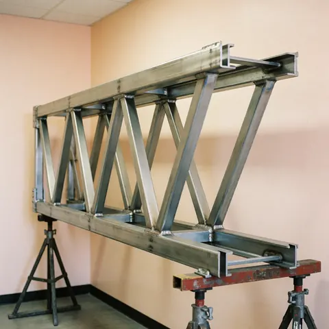 Structure en acier avec traverses et supports métalliques dans un atelier industriel aux murs beiges et à l'éclairage uniforme, adaptée pour catalogues de grues.
