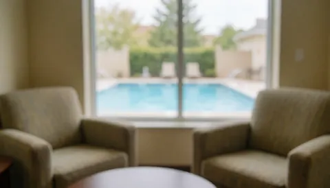 Salon intérieur chaleureux et relaxant avec des fauteuils rembourrés offrant une vue sur l'eau, idéal pour illustrer le confort et la détente liés à l'entraînement de natation.