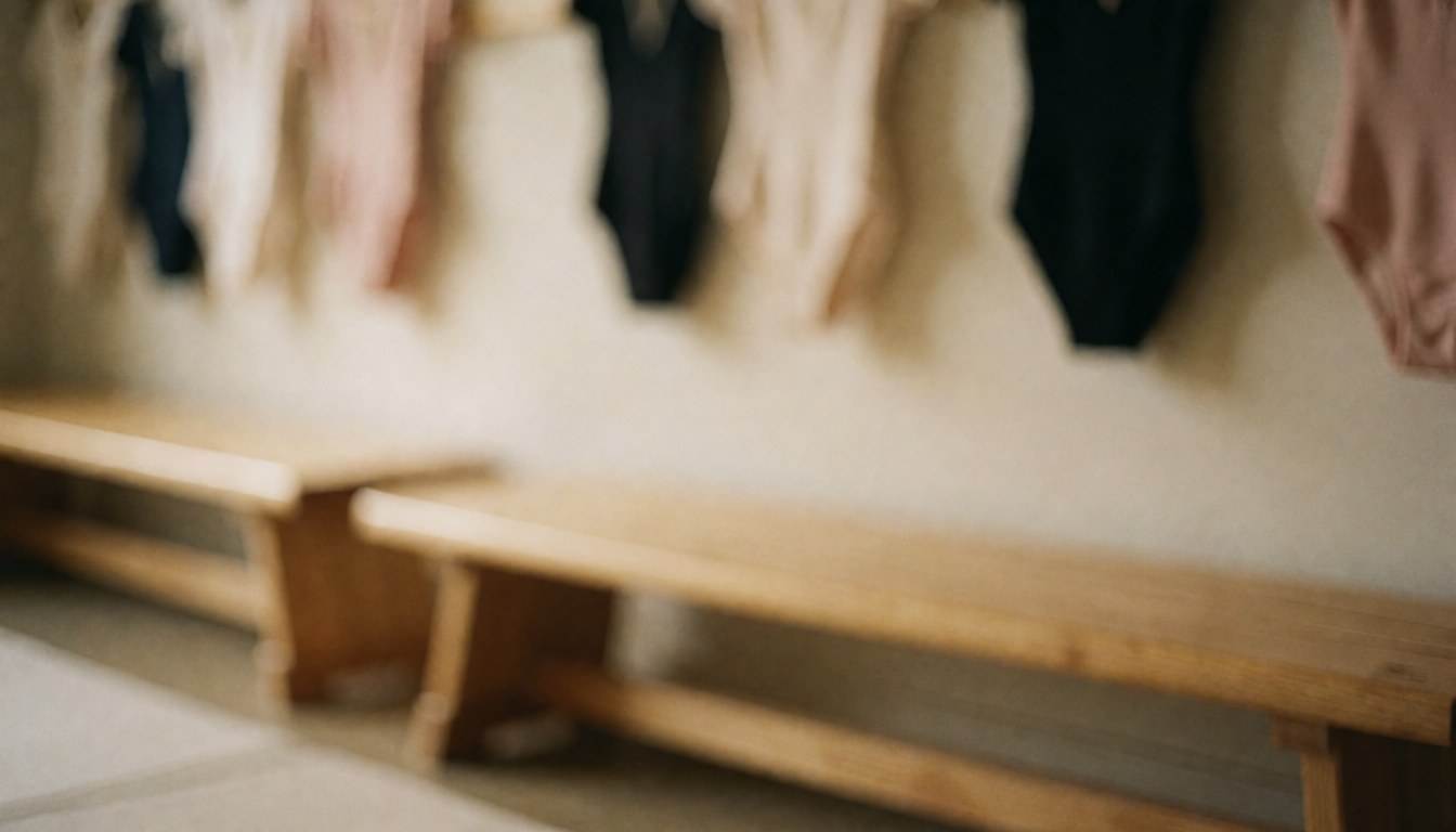 Fond de vestiaire de gymnastique avec des bancs en bois et des leotards suspendus dans des tons doux, idéal pour du texte et du design.
