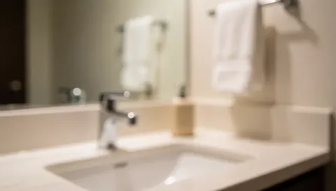 Arrière-plan de salle de bain avec robinet, miroir et serviette blanche, éclairage chaleureux, idéal pour textes commerciaux