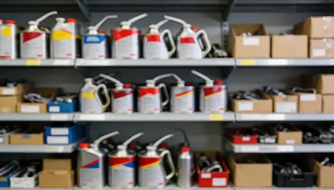 Arrière-plan flou d'étagères métalliques remplies de bouteilles d'huile et de boîtes de rechange pour atelier moto, servant de fond neutre pour l'ajout de texte.