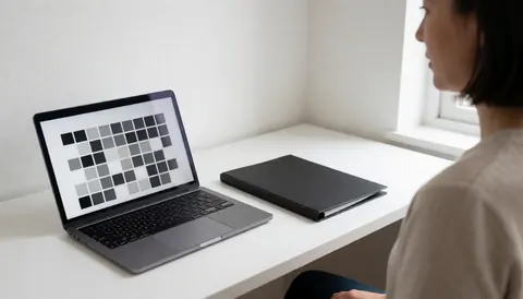 Photographe de portrait sélectionnant une image de fond sur son ordinateur portable dans un bureau blanc éclairé par la lumière naturelle.