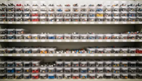 Étagère de stockage remplie de récipients transparents contenant de petits composants électroniques colorés sur fond flou pour texte.