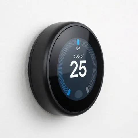 Thermostat digital noir avec écran bleu affichant la température, fixé sur un mur blanc, idéal pour les services de chauffage et de climatisation.