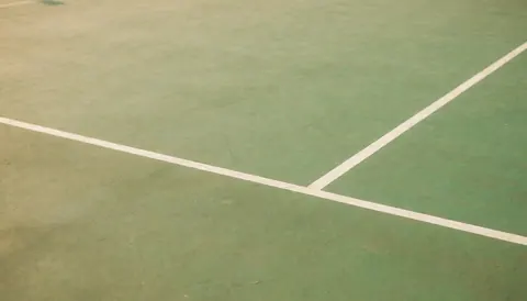 Fond de terrain de sport avec lignes blanches et surface verte, idéal pour textes. Scène calme et propre, parfaite pour les annonces de piscines publiques.