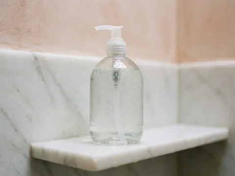 Bouteille transparente avec gouttes d'eau sur marbre blanc, murs terracotta, lumière claire, détail intérieur pour maison de vacances.