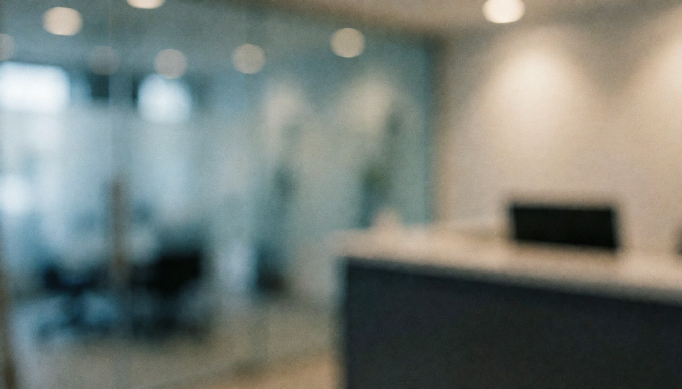 Arrière-plan flou d'une réception de vitrerie avec cloisons en verre, bureau et lumières chaudes, idéal pour superposer des textes.