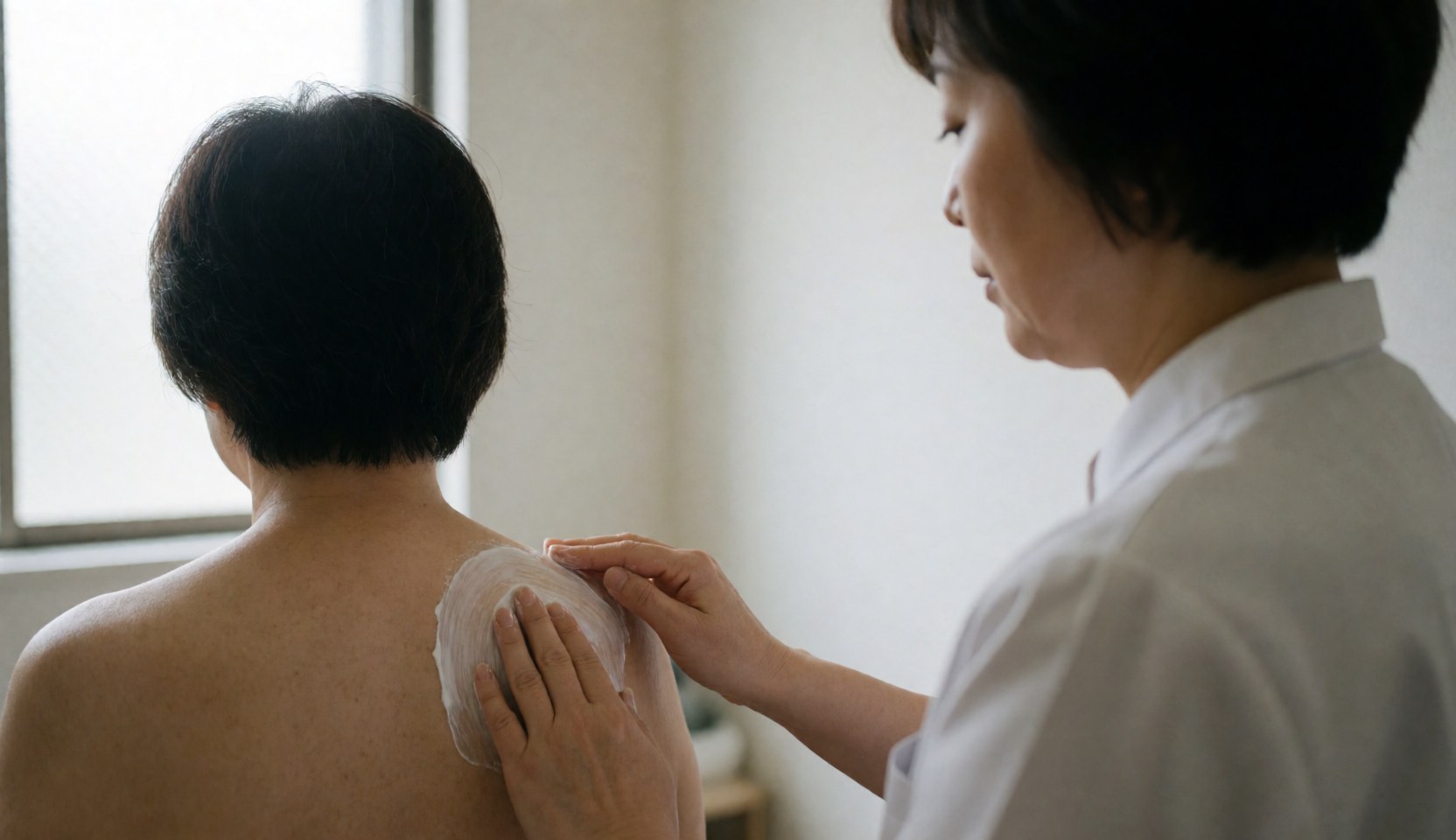 Un thérapeute applique une crème sur l'épaule d'un client dans un cadre professionnel, illustrant une séance de massage.