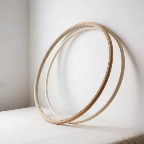 Deux cerceaux de gymnastique en bois clair posés sur une surface blanche avec un éclairage doux, idéal pour la vente d'équipement sportif.