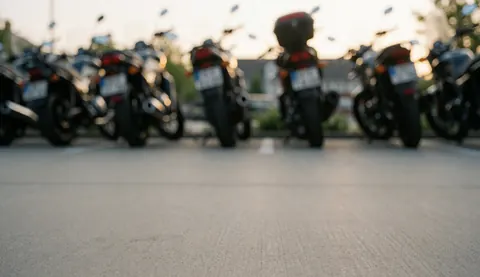 Des motos sont garées sur un sol propre avec un arrière-plan flou, offrant un fond idéal pour illustrer un atelier de réparation de motocyclettes.