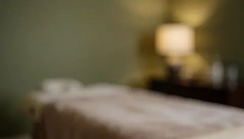 Fond de massage avec table couverte et lampe, murs doux et lumières chaudes, idéal pour textes sur services de massage.