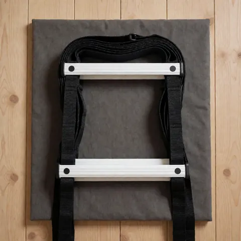 Échelle d'agilité pliée avec structure blanche et bandes noires sur un fond de tissu gris, posée devant un mur en bois clair.