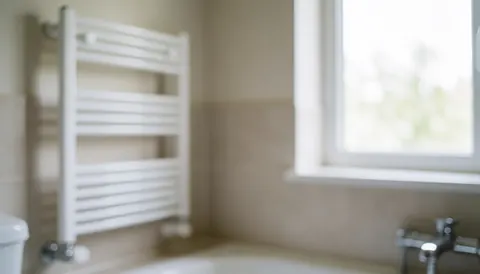 Arrière-plan de salle de bain propre avec un porte-serviettes blanc, des murs neutres et la lumière du jour entrant par une fenêtre, idéal pour les services de nettoyage professionnel.