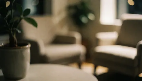 Fond chaleureux composé d'une plante verte en pot et de chaises confortables légèrement floues, créant une ambiance douce et accueillante pour un espace intérieur.
