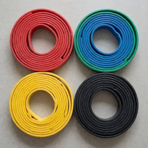 Quatre bandes de résistance enroulées sur un sol en béton clair, dans des couleurs rouge, bleu, jaune et noir, présentées comme un produit d'entraînement physique.