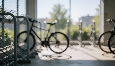 Parking de vélos avec des racks métalliques et des roues floues sur fond de grille et béton, idéal comme arrière-plan textuel pour les instructeurs de cyclisme.