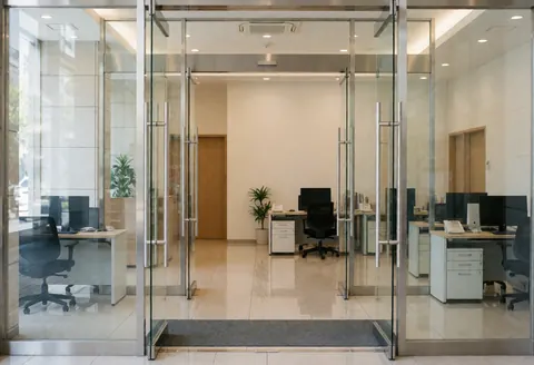 Entrée moderne de bureau avec portes en verre, sol poli et meubles épurés, idéal pour les services de nettoyage professionnel.
