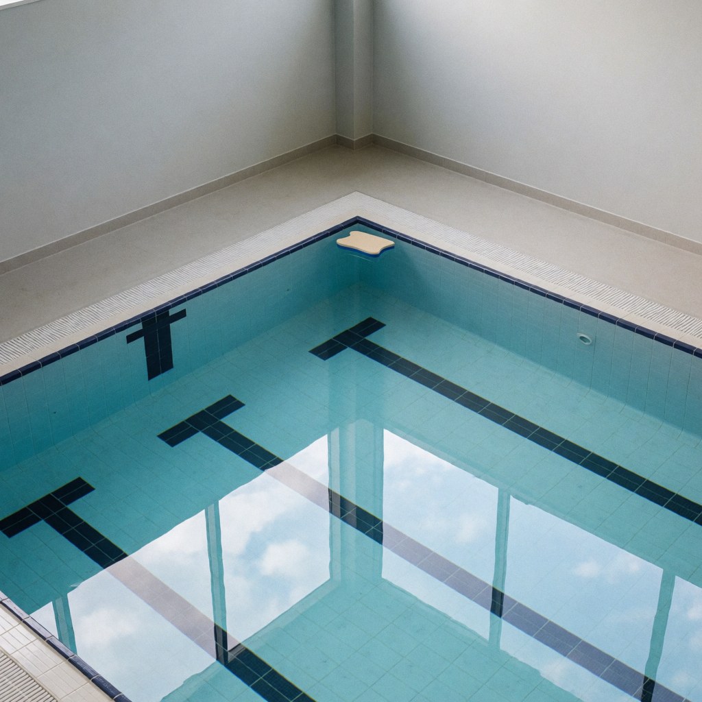 Vue d'une piscine intérieure calme avec une planche à pieds flottante et des lignes de nage visibles sur le fond, idéale pour l'entraînement professionnel.