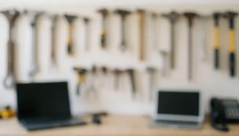 Fond d'atelier avec outils accrochés sur un mur blanc, tables de travail et ordinateurs portables, idéal pour les services de réparation de motos.