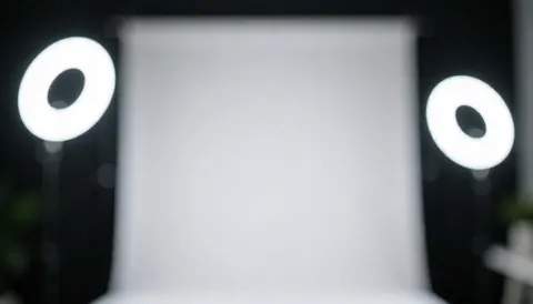 Fond blanc pour photographie avec deux lumières de ring brillantes dans un studio sombre, idéal pour les textes de services de lamination des sourcils.
