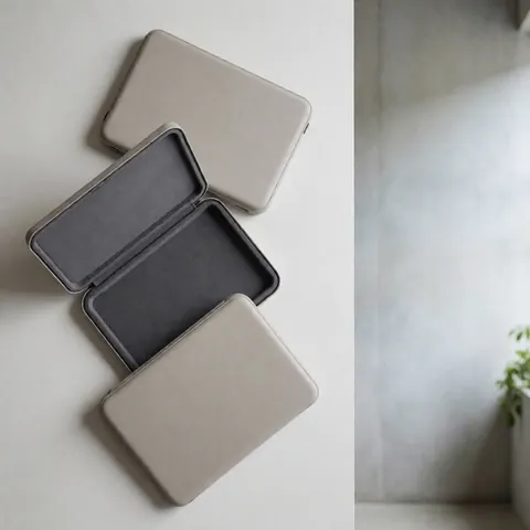 Trois housses neutres pour ordinateur portable avec intérieur rembourré disposées sur une surface blanche, idéales pour un magasin de réparation d'ordinateurs.