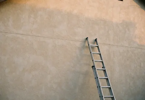 Vue d'un escalier en métal à côté d'un mur extérieur recouvert d'enduit texturé, pertinent pour les professionnels de la peinture résidentielle.