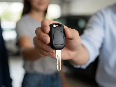 Une main tendant les clés d'un véhicule neuf à un client satisfait lors de la remise du matériel dans un concessionnaire automobile.