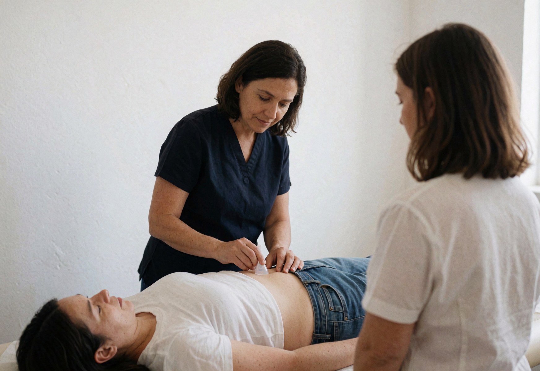 Un thérapeute applique des ventouses sur l'abdomen d'un client dans un cabinet lumineux aux murs blancs.