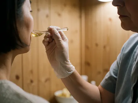 Un professionnel applique du miel sur le visage d'un client dans un salon de beauté aux murs en bois et à l'éclairage chaleureux.