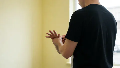 Un entraîneur de boxe enveloppe soigneusement la main d'un client dans un gymnase aux murs clairs et à la lumière naturelle, offrant un service personnalisé.
