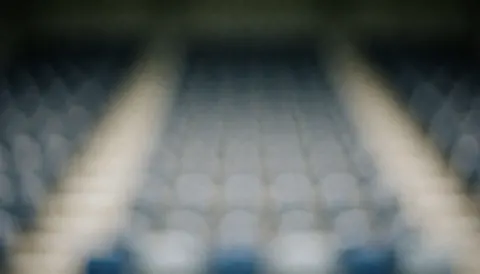 Fond de gradins de stade avec effet bokeh, dégradé de gris et de bleu, idéal pour les textes de coach de football.