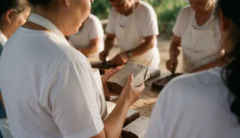 Un ouvrier emballe du cacao en blocs dans une aire de séchage en plein air sous lumière naturelle.
