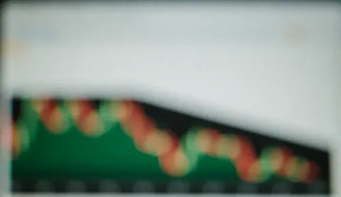 Graphiques financiers flous avec effet bokeh sur écran, servant de fond pour des textes liés aux finances et à la banque.