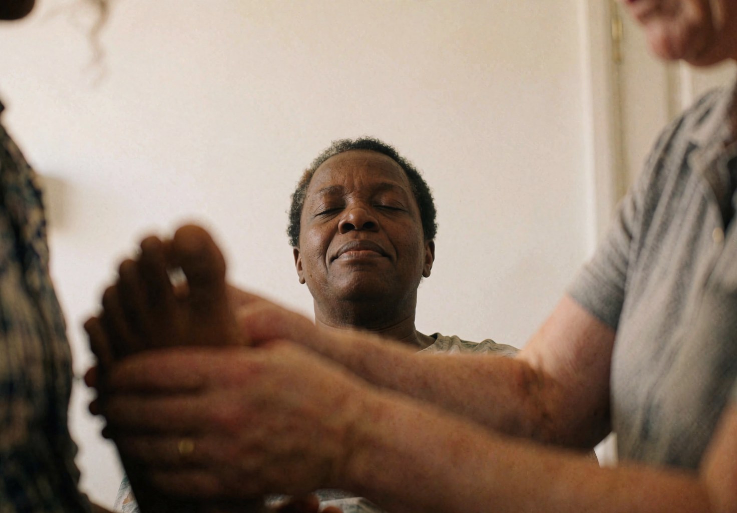 Des mains pratiquant la réflexologie sur le pied d'une cliente dans un cadre professionnel avec un fond blanc.