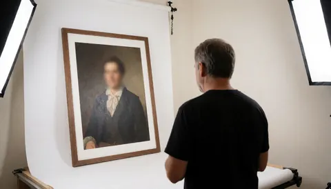 Un photographe de portrait examine un portrait encadré dans un studio avec un fond blanc et des lumières softbox.