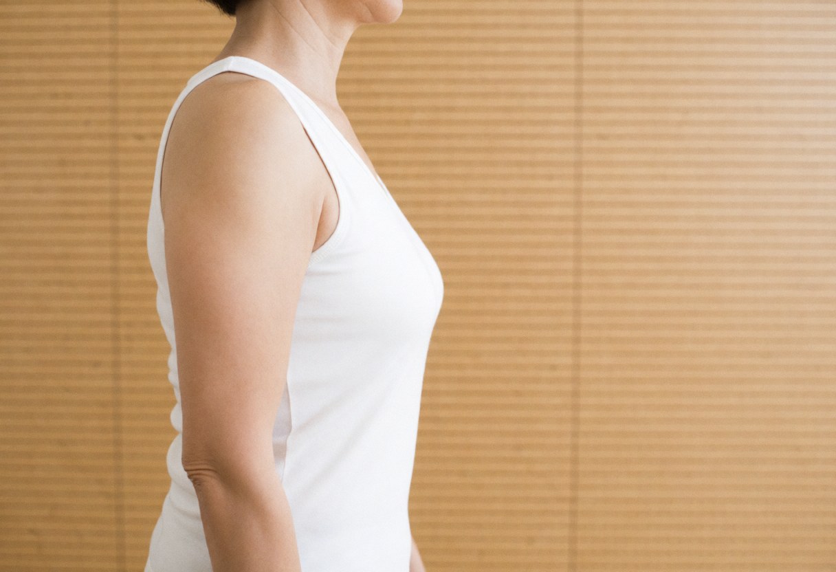 Silhouette de profil d'une femme adulte vêtue d'un t-shirt blanc, se tenant devant un mur en bois avec une lumière naturelle douce.