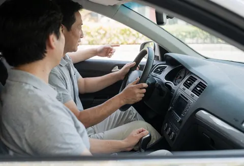 Instructeur de conduite pointant vers l'étudiant pendant qu'il conduit une voiture manuelle, scène réaliste d'auto-école.