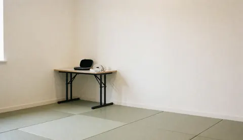 Table avec protège-dents et ceinture de gi dans un dojo avec tatamis et murs crème, idéal pour la page d'accueil d'un site web d'instructeur de karate.