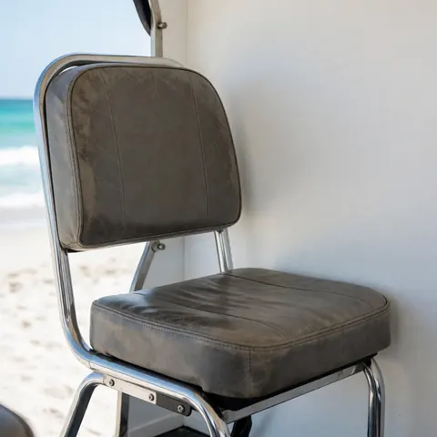 Siège de vélo-taxi en cuir gris usé avec cadre chromé sur fond de plage et océan turquoise.