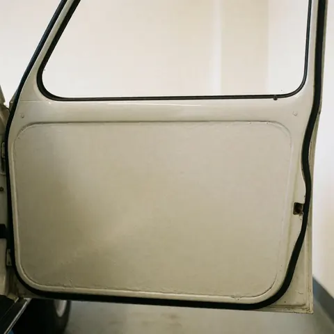 Porte de véhicule présentant une finition lisse et uniforme avec des reflets nets sur fond blanc chaud, illustrant un service professionnel de carrosserie.