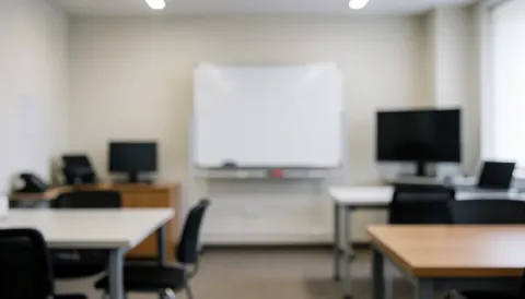 Arrière-plan flou d'un espace de formation photo avec tables, chaises, tableau blanc et écrans, idéal pour superposer du texte.