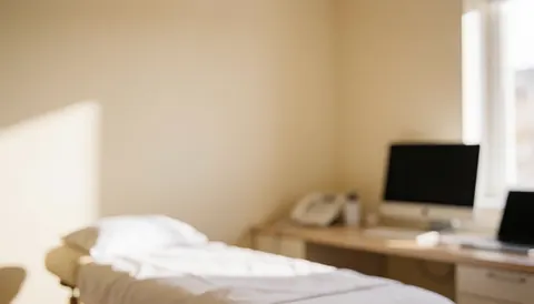 Lit de massage professionnel avec draps blancs, placé dans une pièce aux murs beige et à la lumière naturelle, servant de fond pour des services de bien-être.