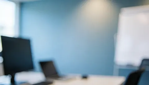 Arrière-plan professionnel avec écrans et tableau blanc, idéal pour du texte, ambiance de bureau moderne avec mur bleu et lumière douce.
