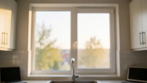 Arrière-plan de cuisine moderne avec une nouvelle fenêtre en verre, un cadre blanc et une lumière chaude, idéal pour les services de réparation de fenêtres.