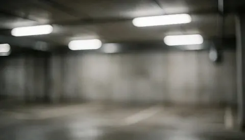 Arrière-plan flou d'un garage souterrain avec des murs en béton et des lumières fluorescentes, idéal pour les services de remorquage