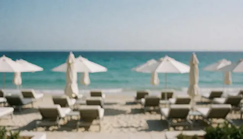 Arrière-plan de plage avec chaises et parasols, idéal pour du texte, eau turquoise et sable clair