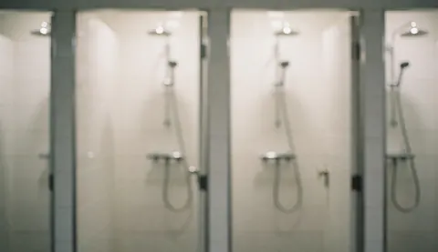 Douches équipées de robinets métalliques dans une salle de bain aux murs carrelés de blanc, offrant un fond neutre et propre adapté aux textes commerciaux.