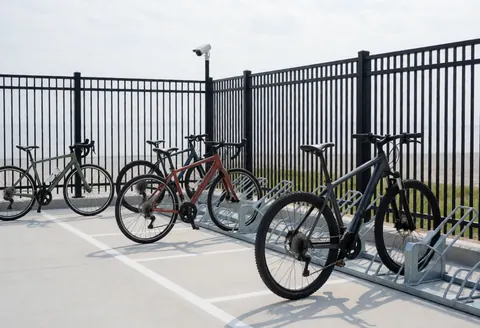 Support métallique pour vélos avec caméra de surveillance et sol en béton marqué, idéal pour les professionnels du cyclisme.