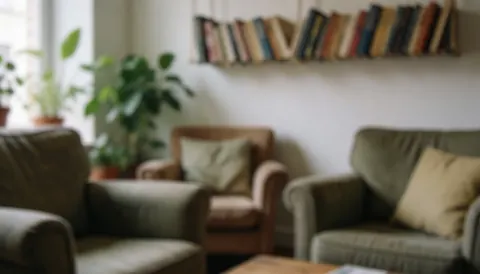 Arrière-plan de salon avec fauteuils rembourrés, étagère à livres suspendue et plantes vertes, idéal pour des textes liés à l'hébergement.